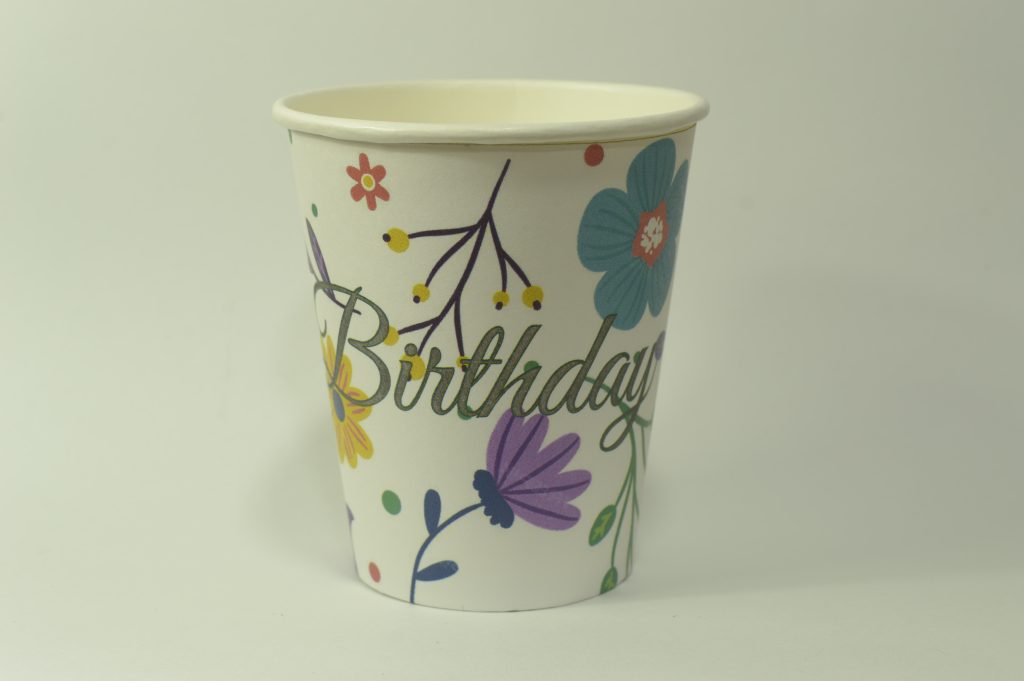 Vaso de cumpleaños con flores de colores morado y azul, con letrero de happy birthday