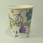 Vaso de cumpleaños con flores de colores morado y azul, con letrero de happy birthday