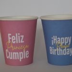 Par de vasos con fondo de color, vaso rojo con letreo de happy birthday princess y vaso azul con letrero de feliz cumple principe