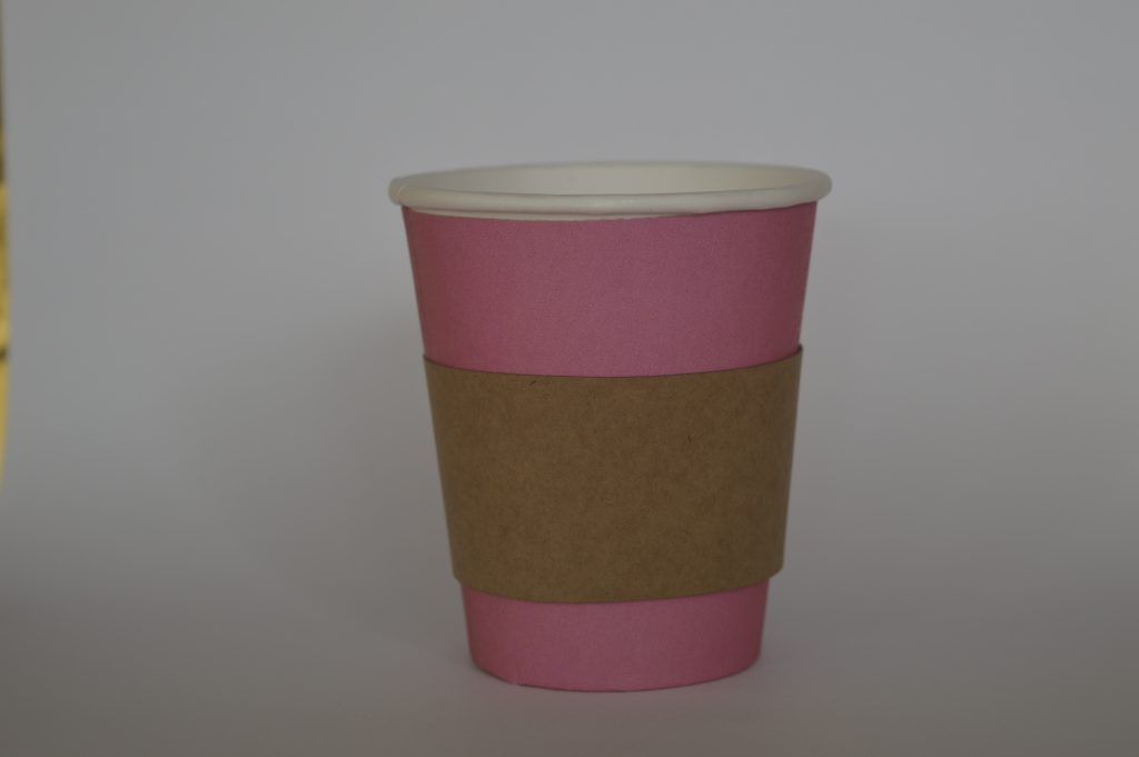 Aislador de calor en cartón puesto en vaso de color de fondo azu