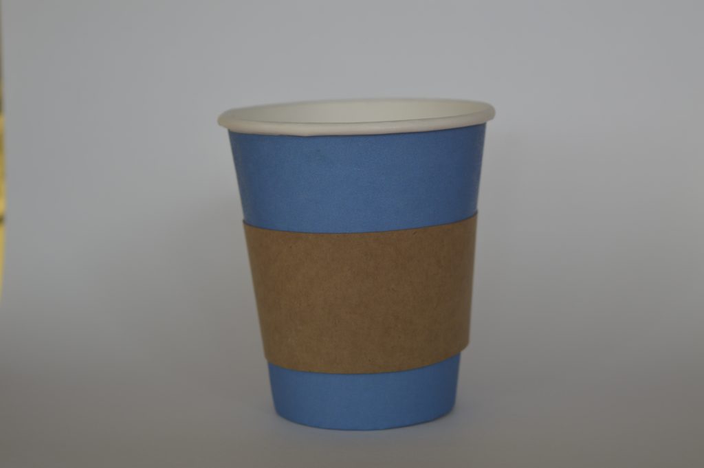 Aislador de calor en cartón puesto en vaso de color de fondo azul