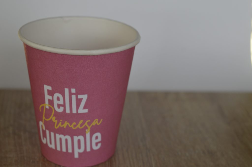 Vaso de color rojo con letrero de feliz cumple princesa sobre una superficie de madera